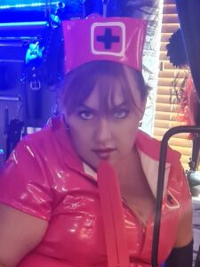 Mistres Gia in a red, PVC Nurse dress w2ith rubber tause